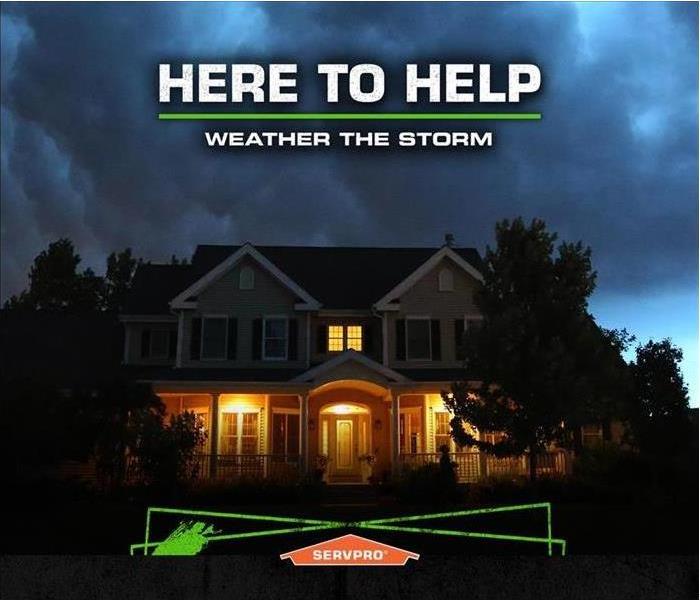 Large house that is about to get hit with a storm with SERVPRO logo. 