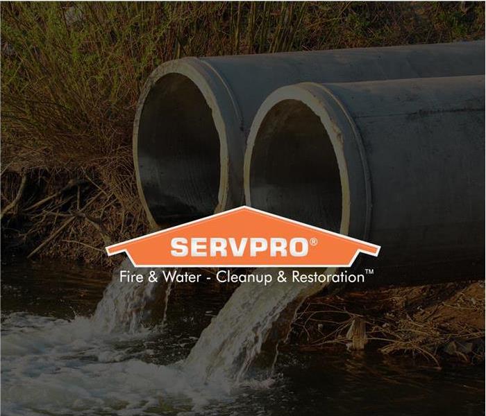 Two sewage pipes draining into what looks like more contained water with the SERVPRO logo on top of the photo